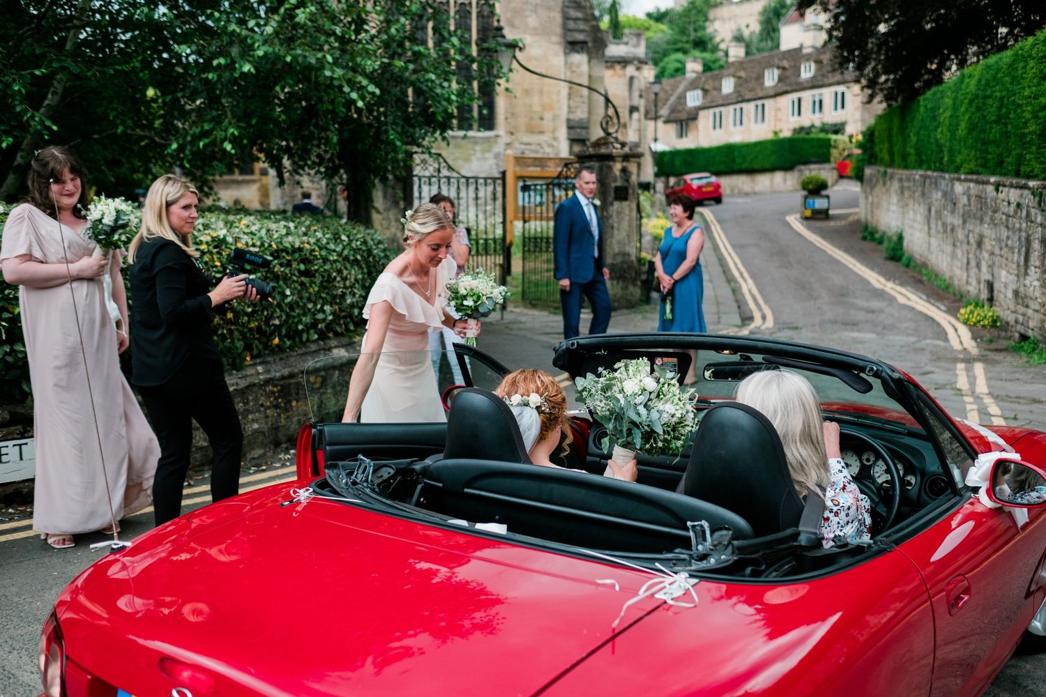 Classic red convertible sports car parked outside historic stone building.