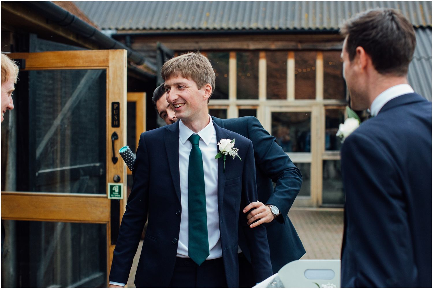 Groomsmen sharing a laugh outside a modern venue before the ceremony.
