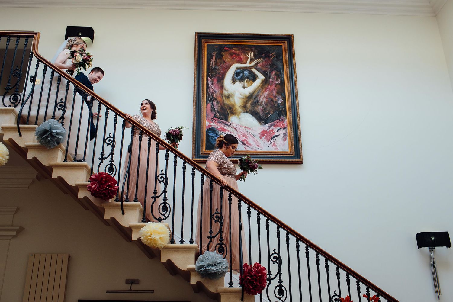 Elegant staircase with dark wood railings and white walls decorated with framed artwork.