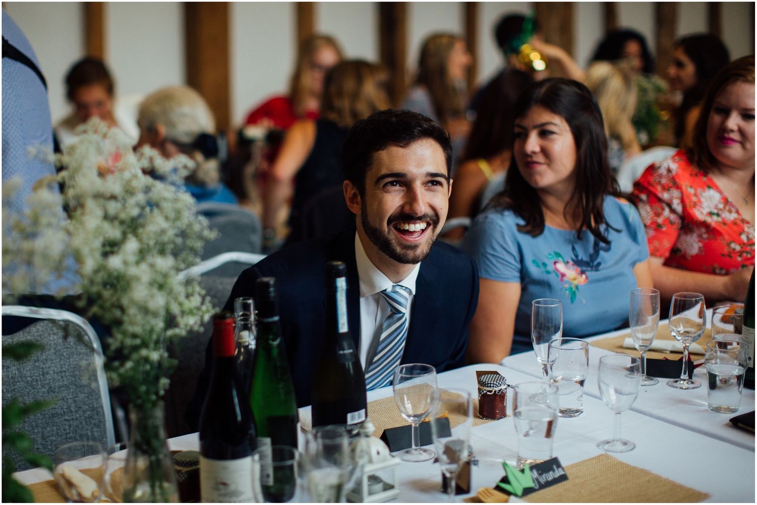 Wedding reception guests laughing and socializing at indoor venue.