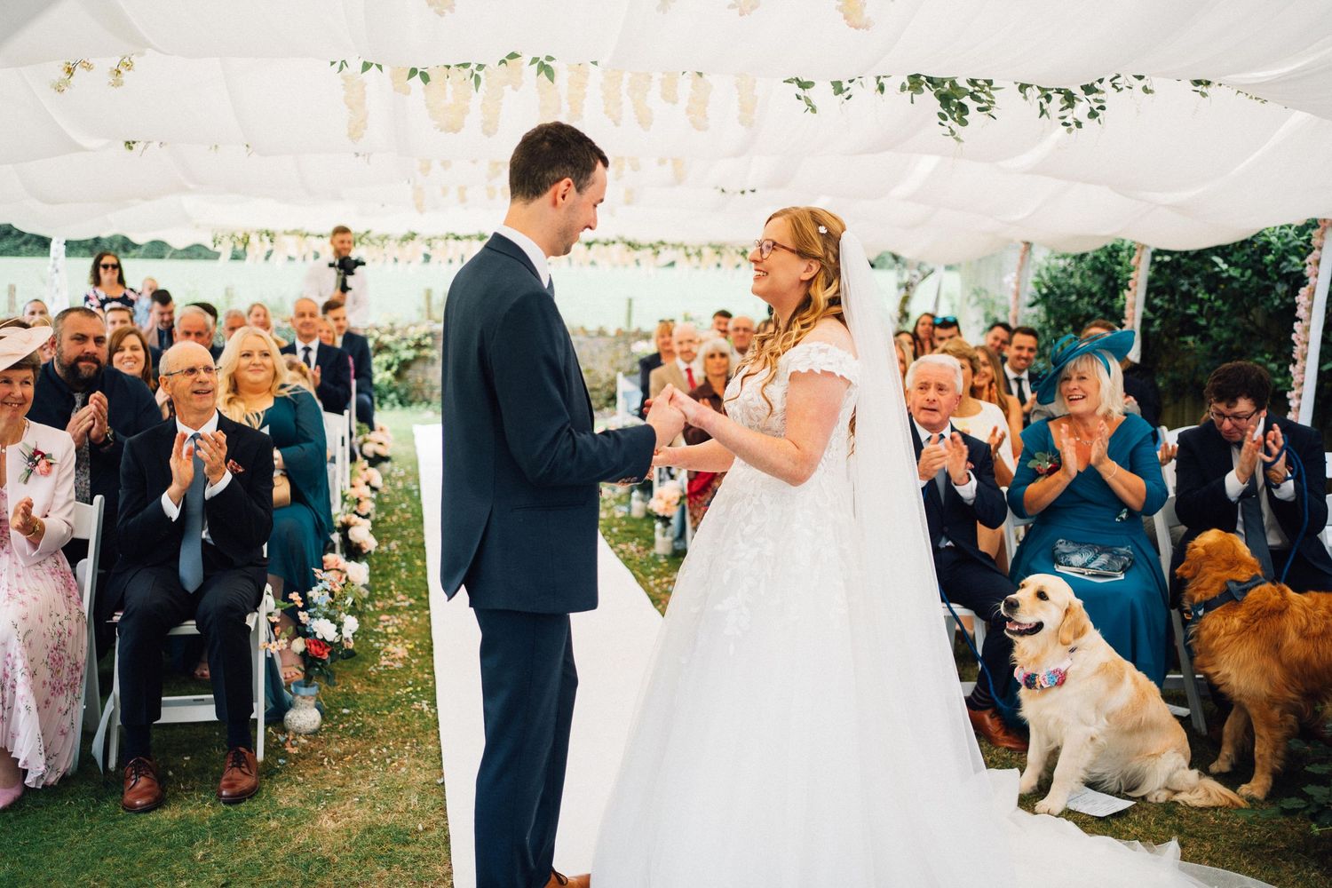 Wedding guests shower newlyweds with confetti and flower petals during outdoor garden celebration.