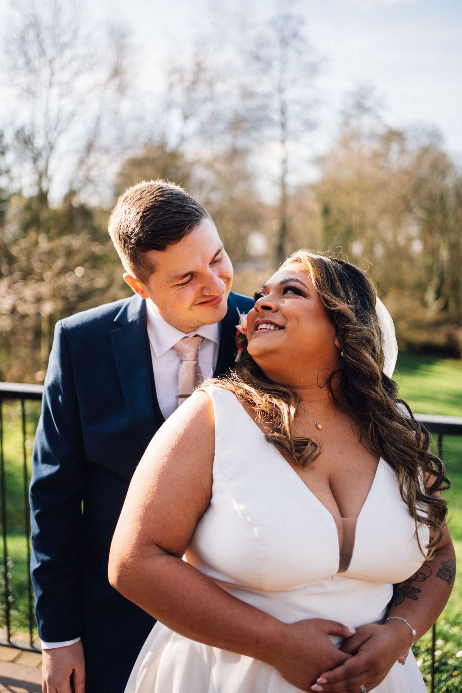 Romantic outdoor wedding photos of a couple embracing and laughing in natural sunlight.