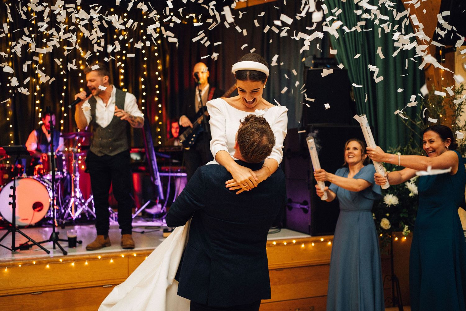 Wedding reception dance floor with string lights and confetti falling during a celebratory moment.