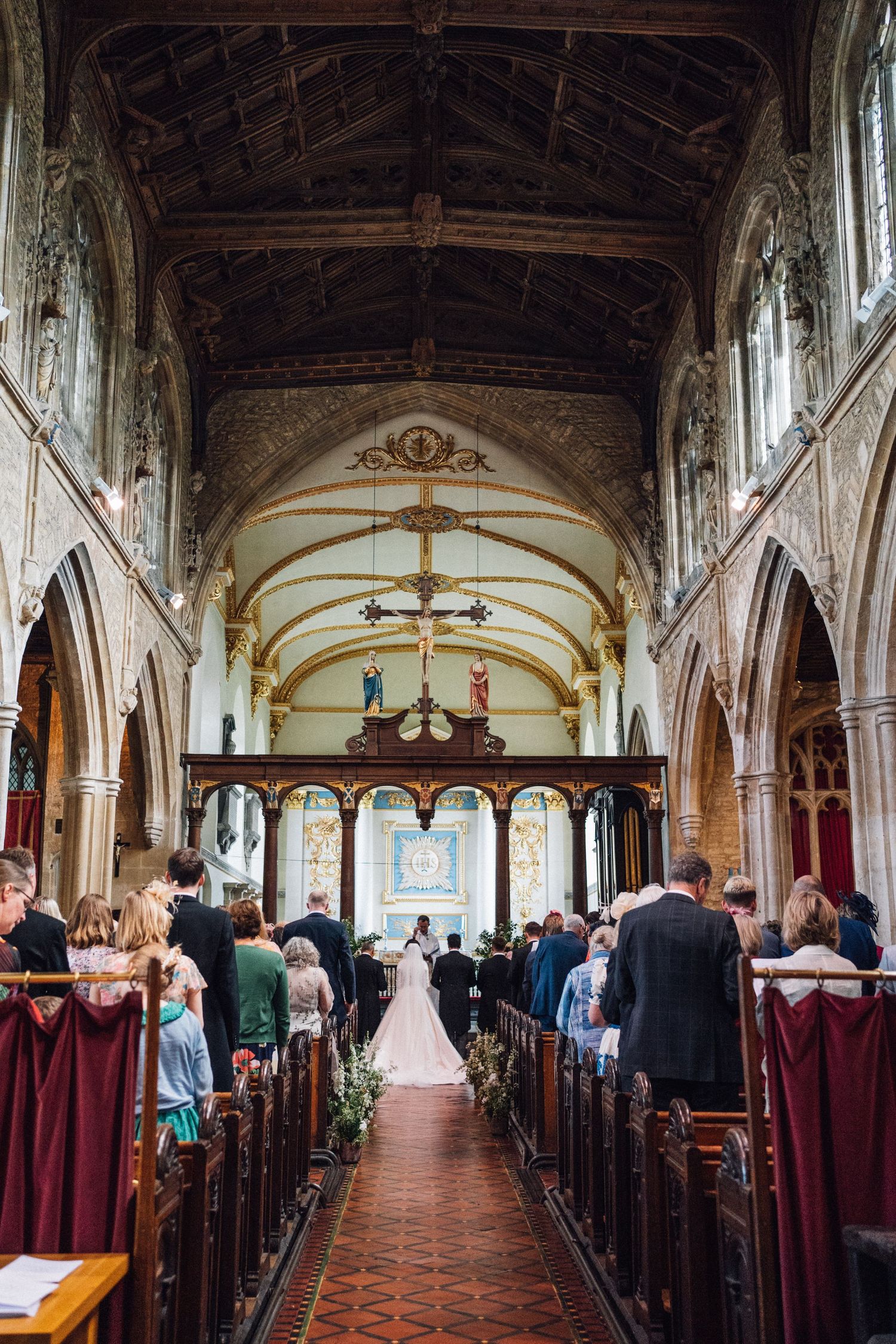 A traditional church wedding ceremony taking place in a grand Gothic cathedral with vaulted ceilings and stained glass windows.
