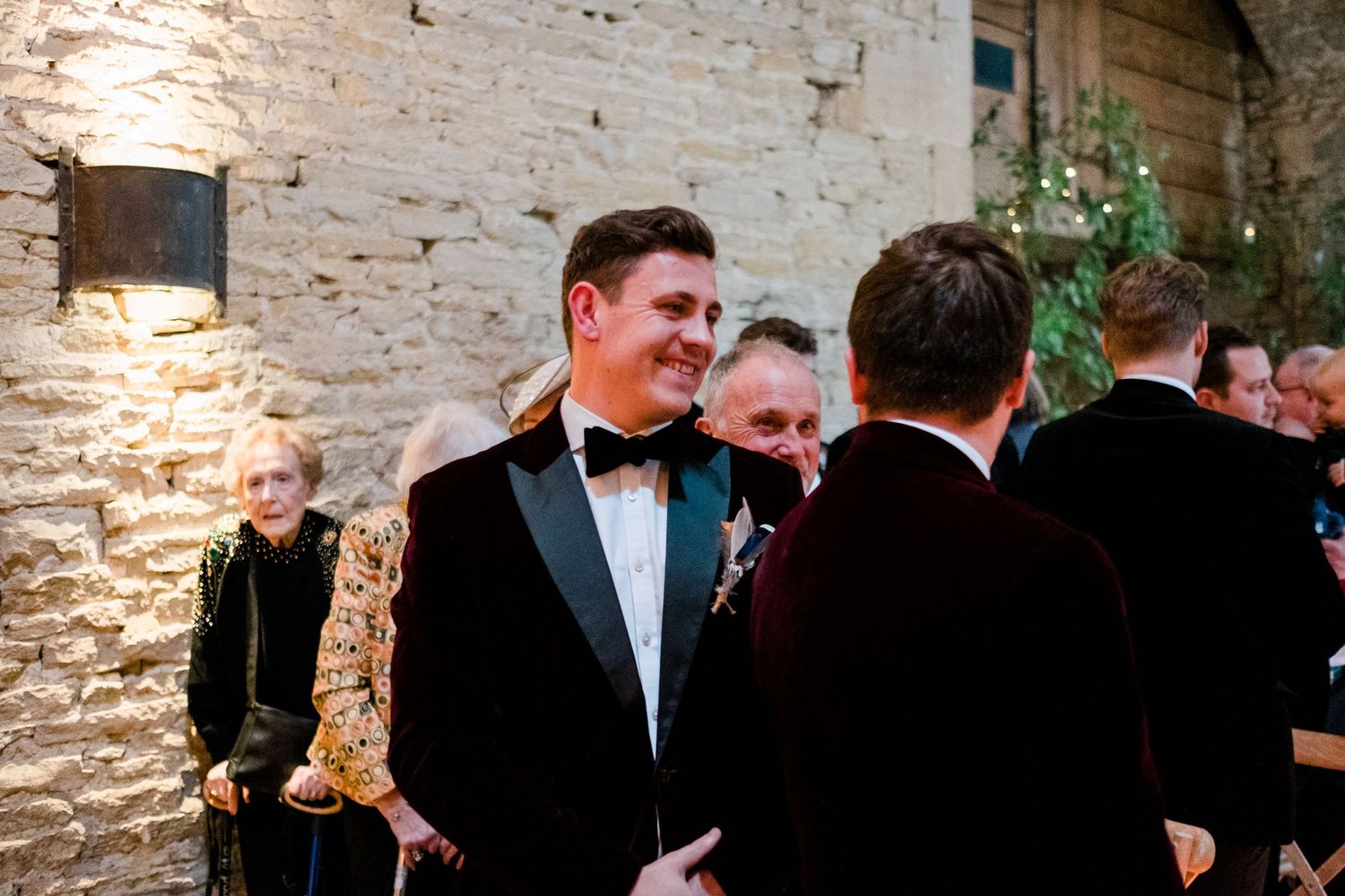 Formal celebration gathering with guests in black tie attire at stone-walled venue.