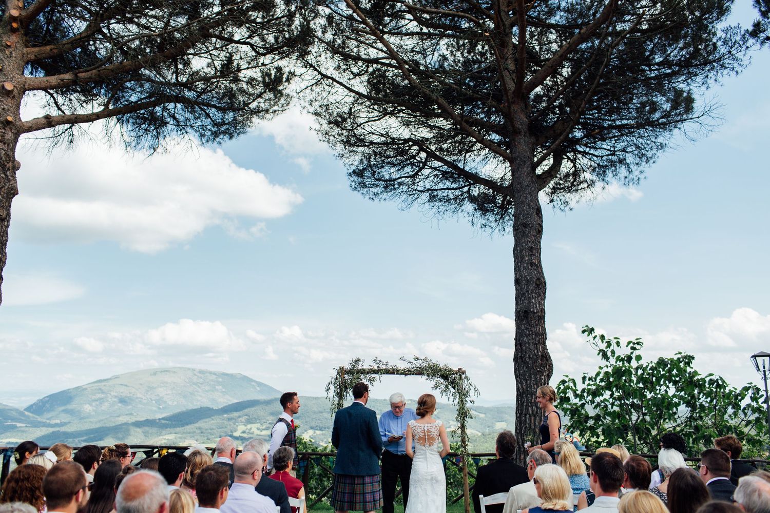 Outdoor wedding ceremony setup with pine trees and mountain views in the background.