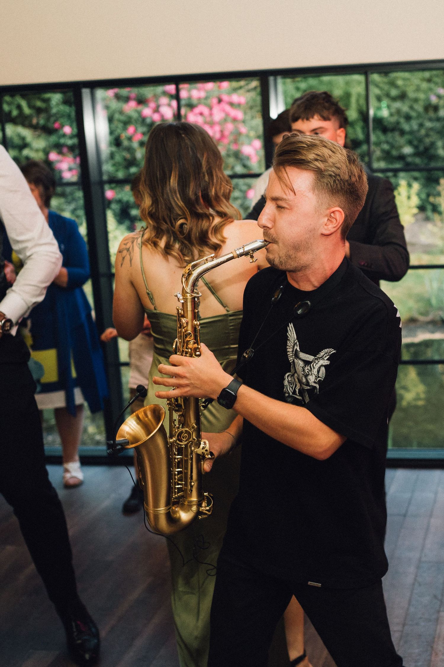 Saxophone player performing at a wedding reception with guests dancing.