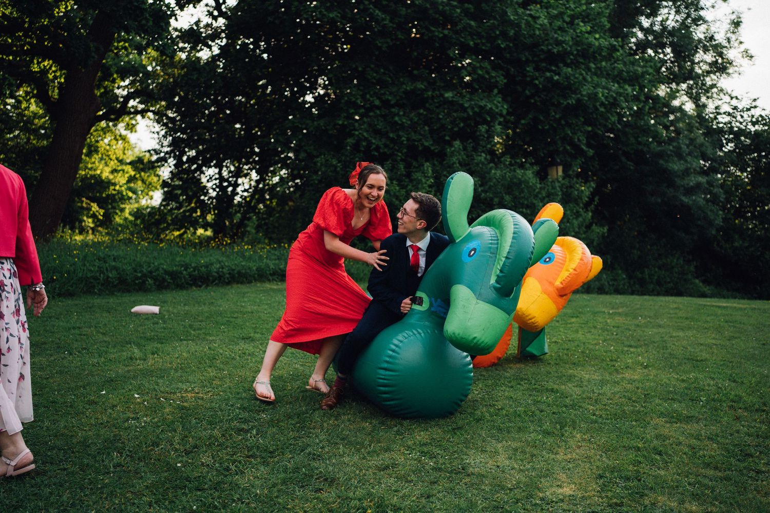Playful wedding celebration with inflatable dinosaur decorations in an outdoor garden setting.
