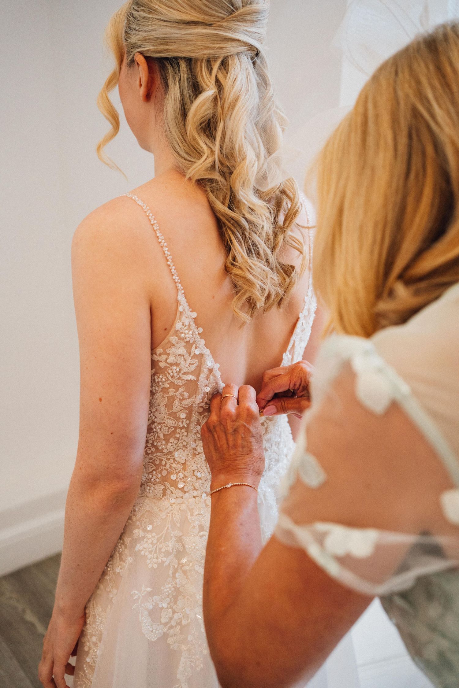 Close-up sequence of a bride getting her wedding dress buttoned up during preparation.
