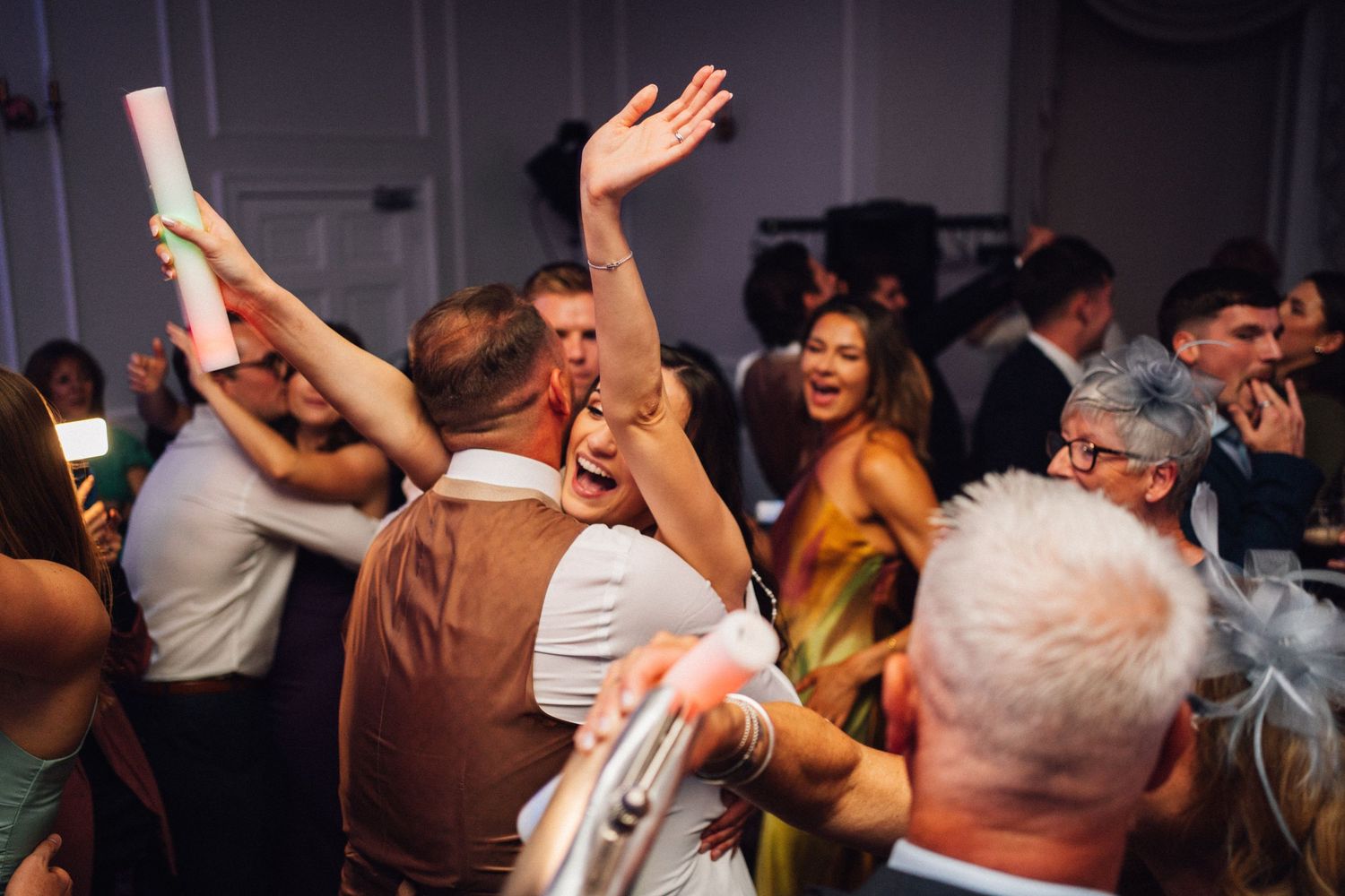 Energetic wedding reception with guests dancing and celebrating on a crowded dance floor.