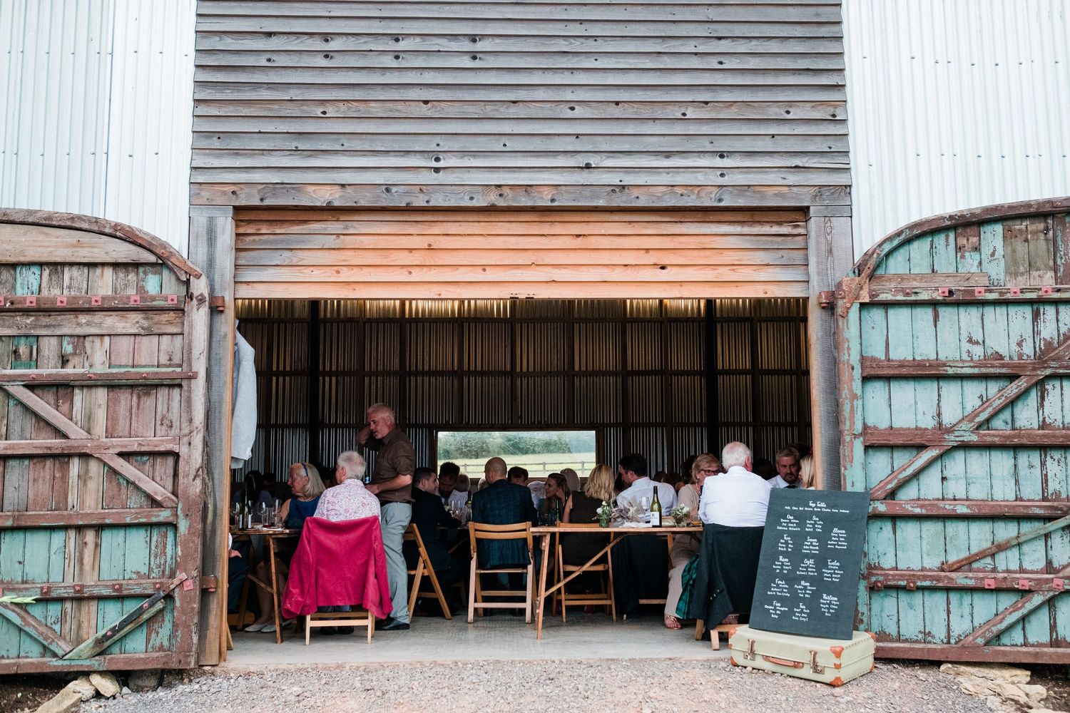 Large barn doors open to reveal an interior setup for a wedding reception.