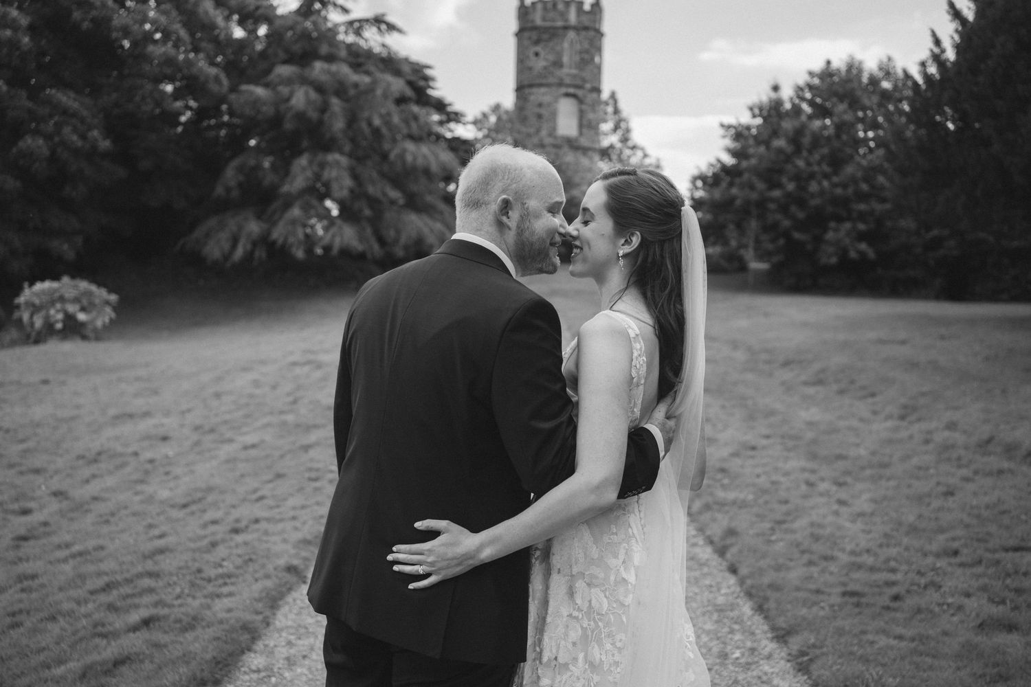 Black and white wedding portrait with church tower in background.