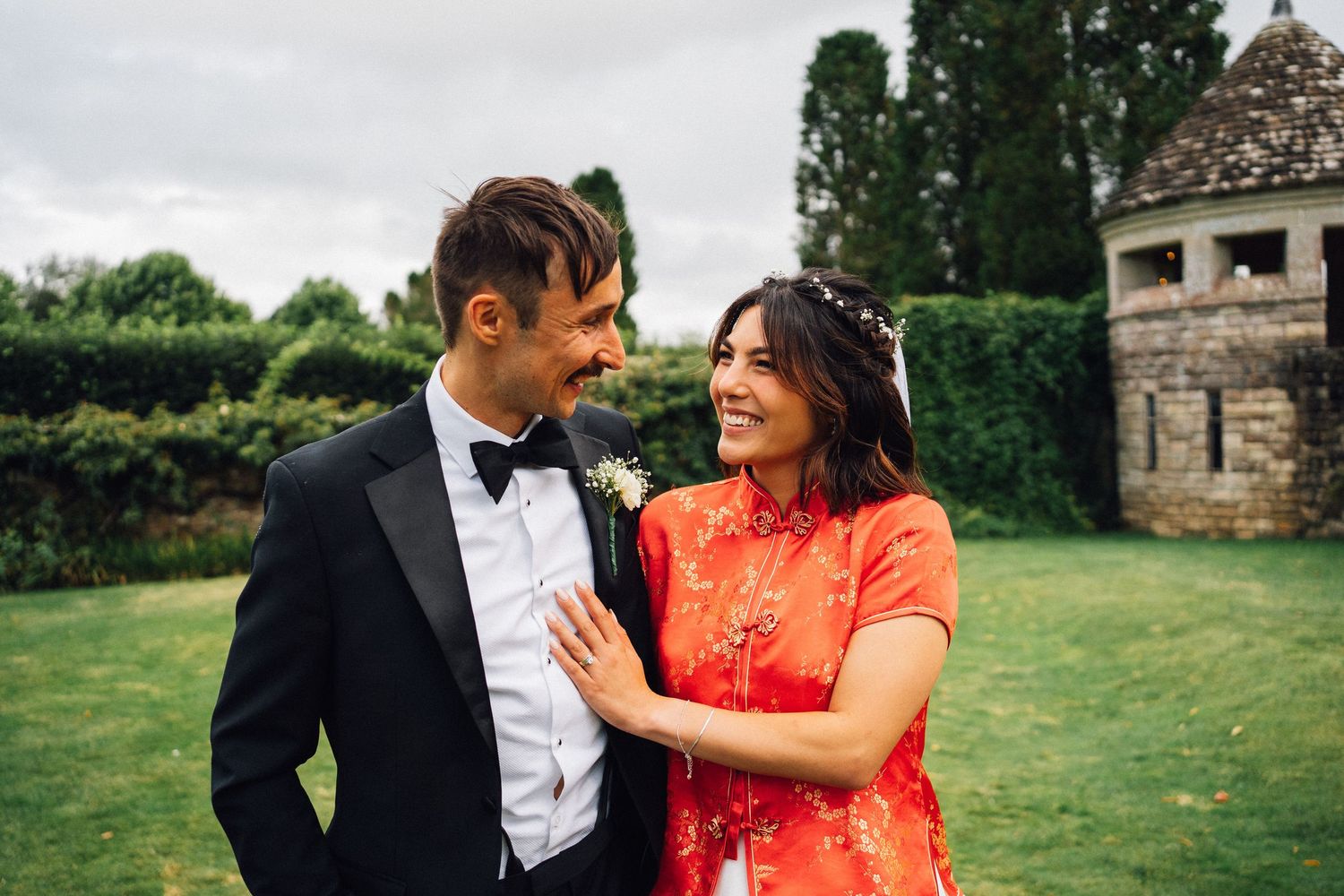 Newlyweds share intimate moments on grassy lawn during outdoor wedding photoshoot.