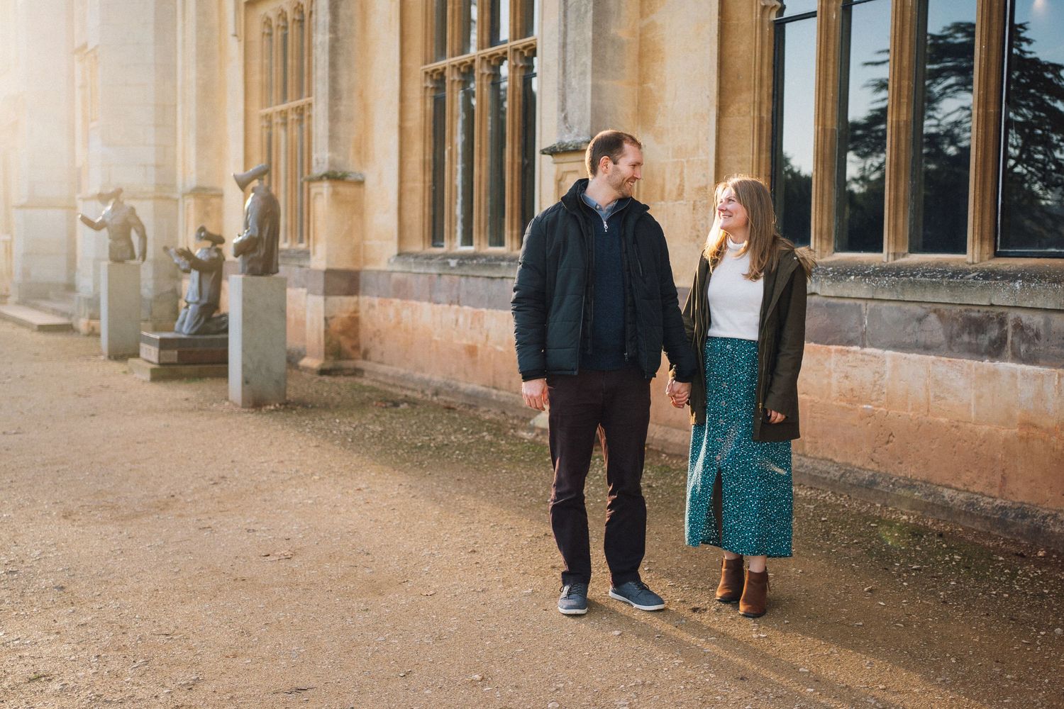 A couple strolls together along the exterior of a grand historic building.