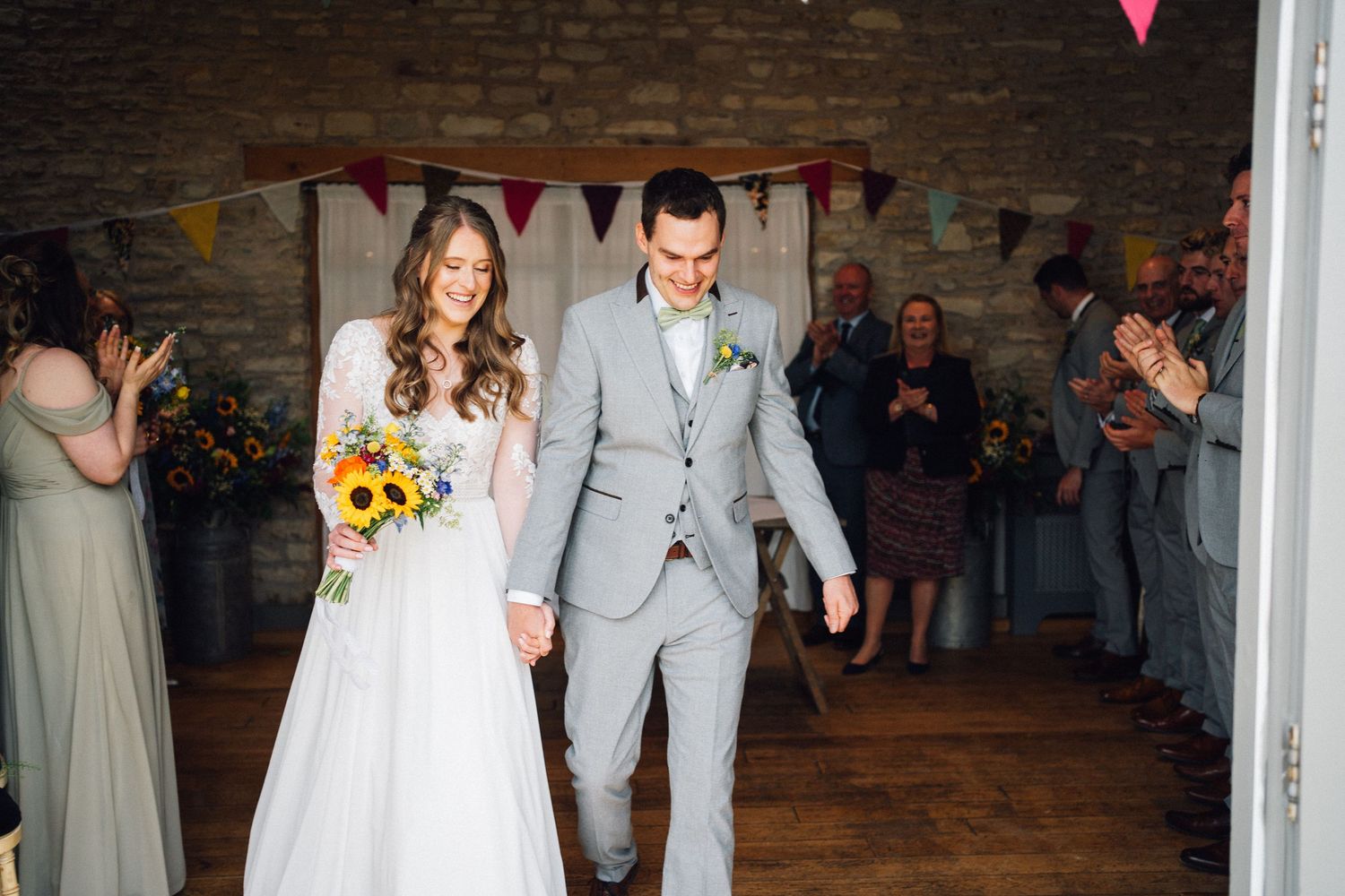 Wedding ceremony aisle decorated with colorful bunting flags in a rustic stone venue.
