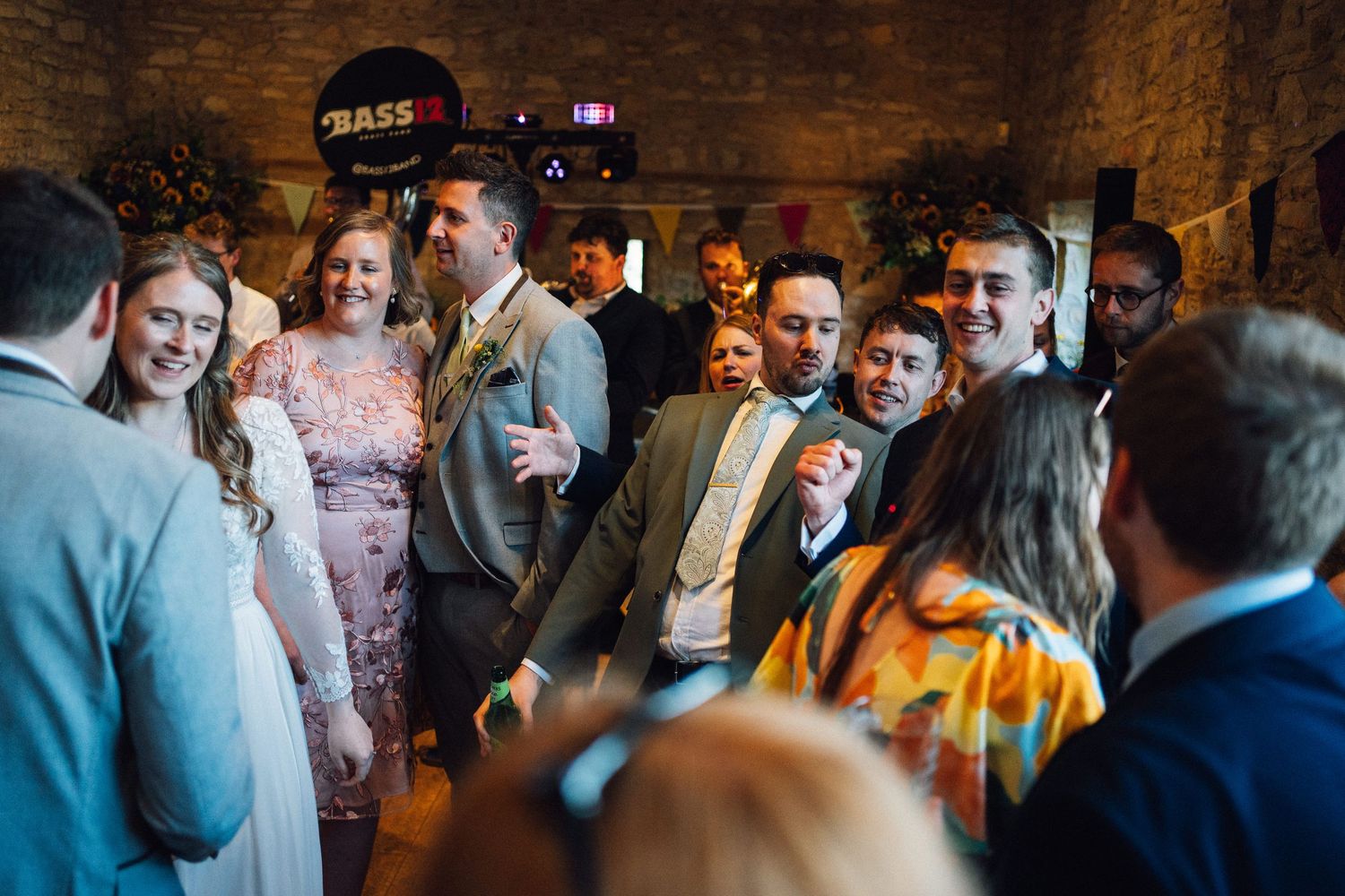 Guests mingling and socializing at a rustic wedding venue with brick walls and natural lighting.