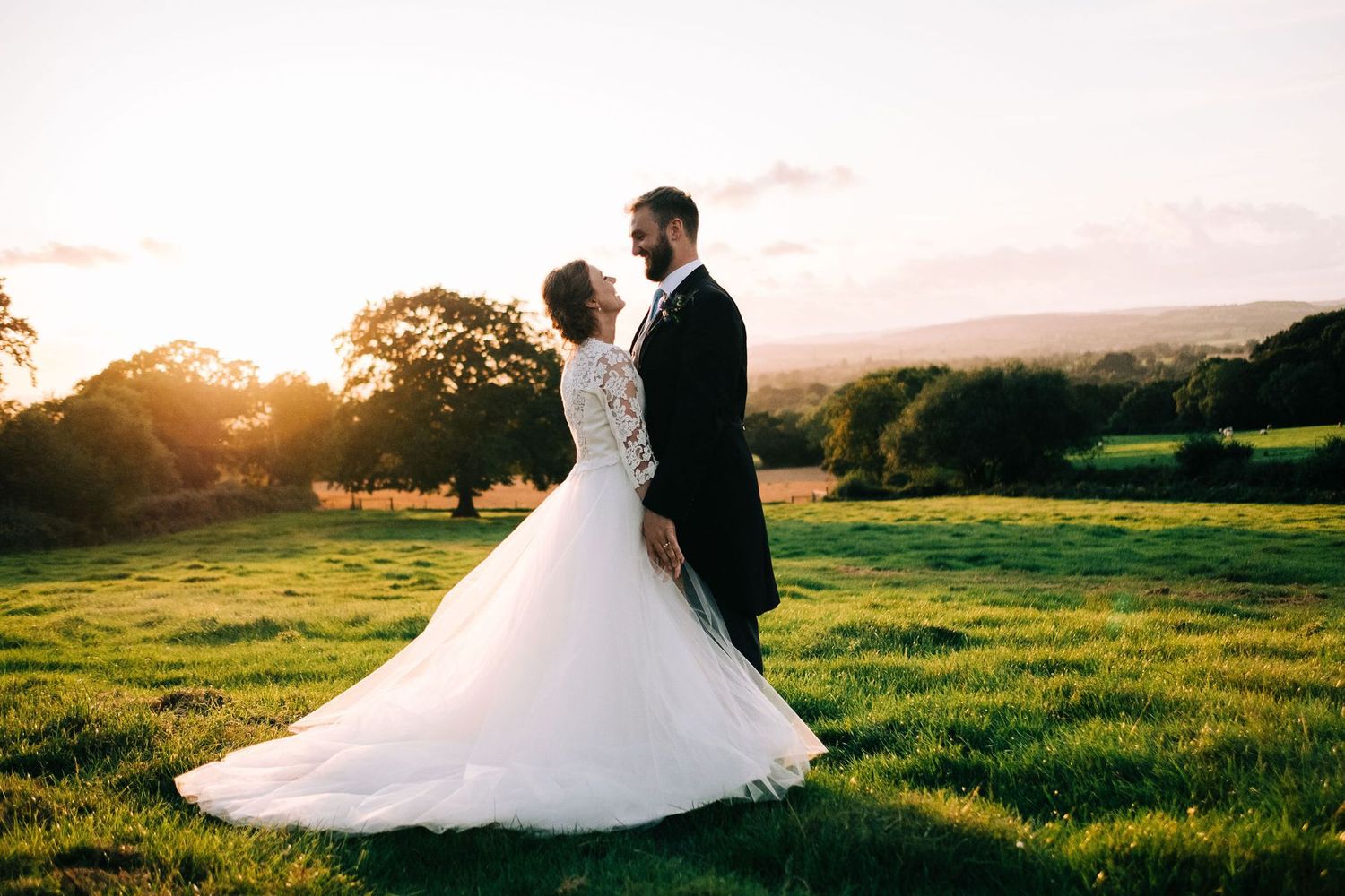 Romantic sunset wedding portraits in a golden-lit meadow.