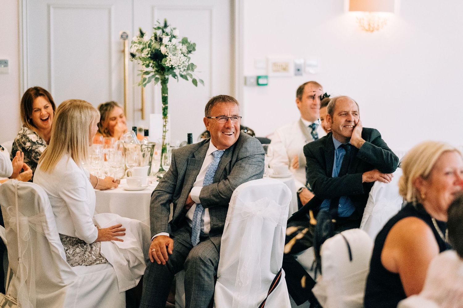 Wedding reception guests enjoying animated conversations at decorated indoor venue.