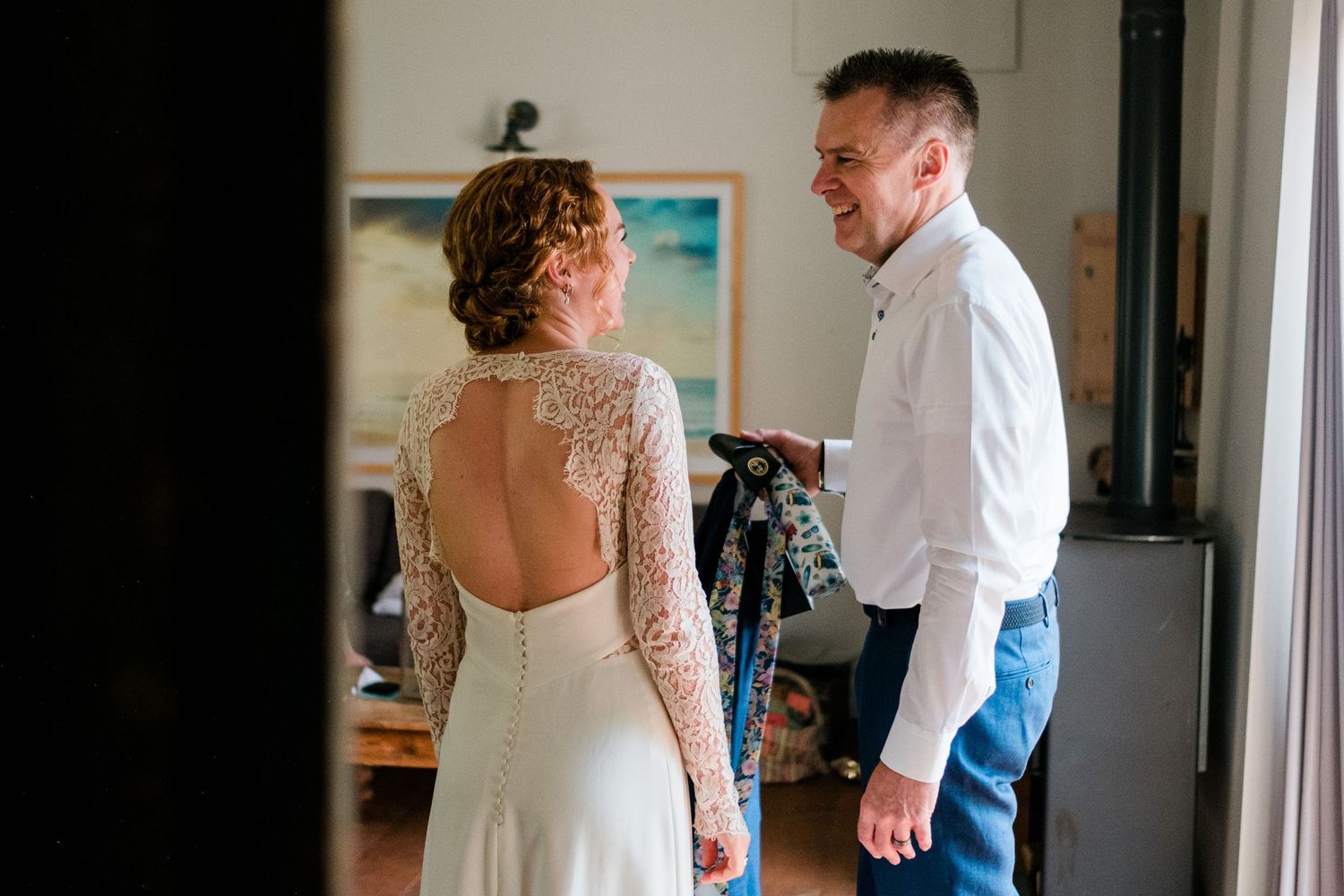 Tender first look moment between couple in a sunlit room with white decor.