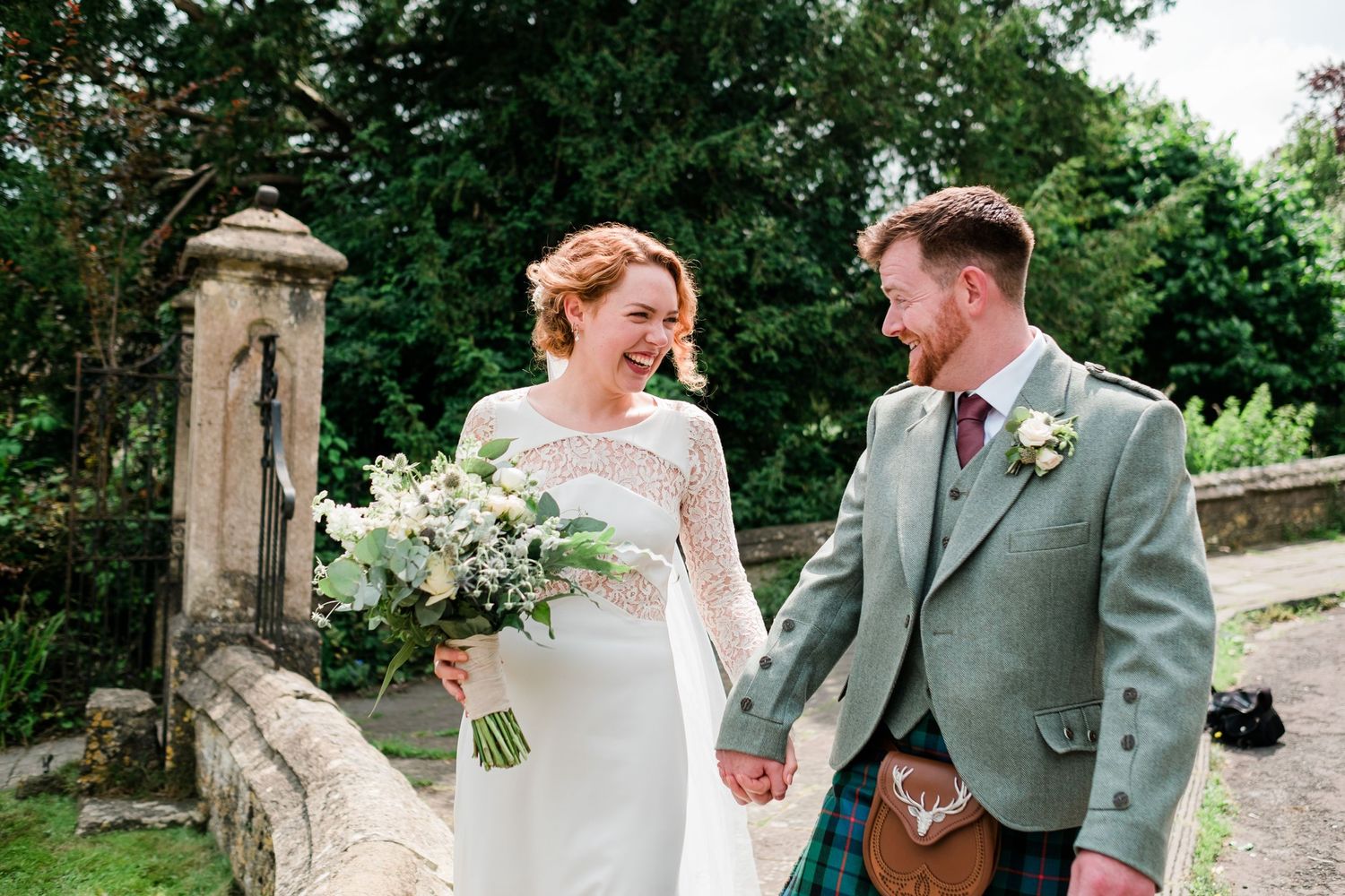 A happy couple sharing a moment together on their wedding day near a stone pillar.