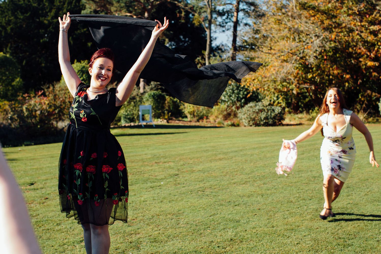 Guests celebrate with energetic poses on a sunny lawn during a wedding reception.