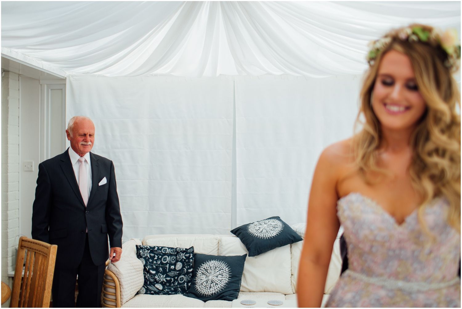 Emotional first look moment in a white tent-draped room with elegant decor.