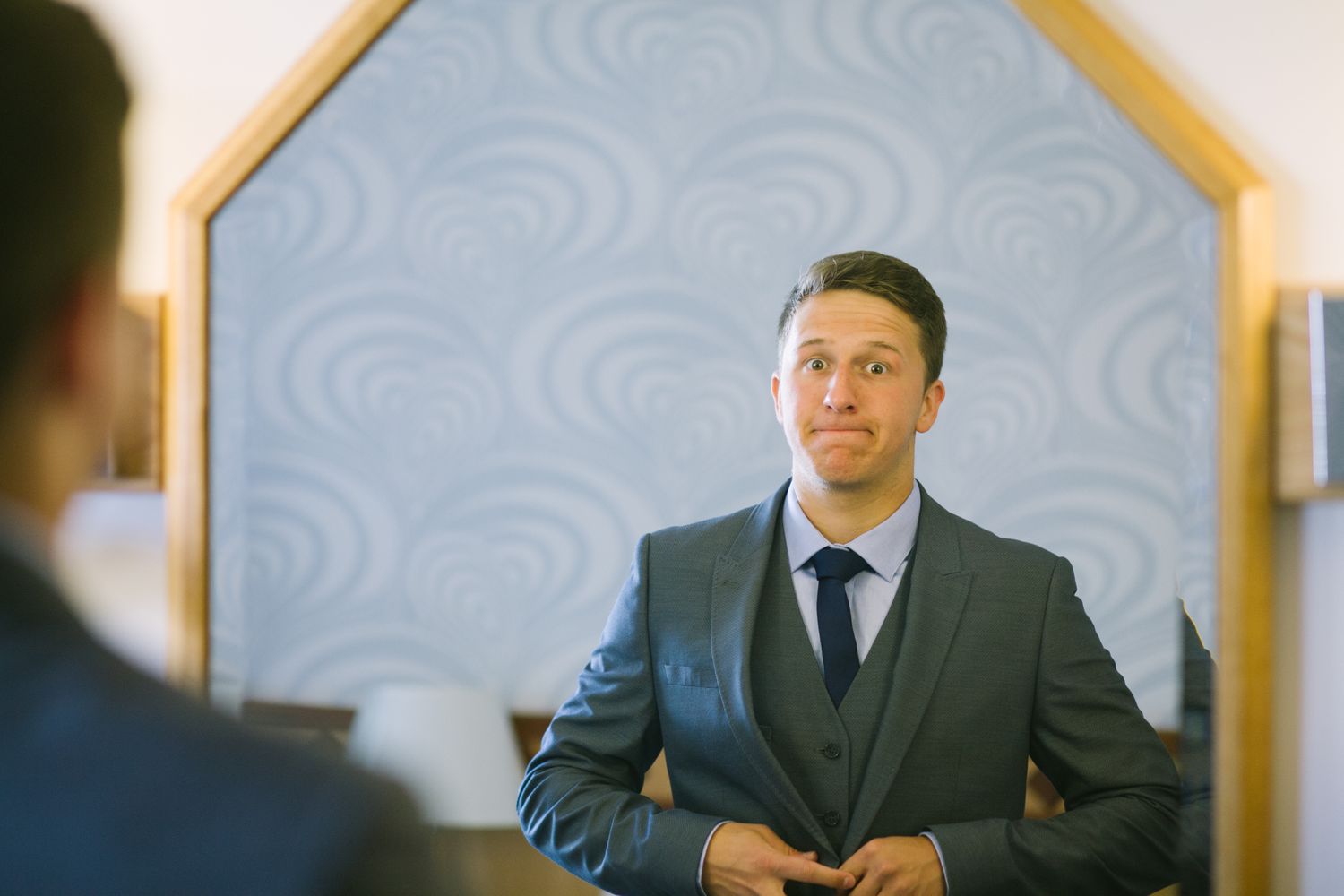 Men in formal suits gathered in hotel room before ceremony.