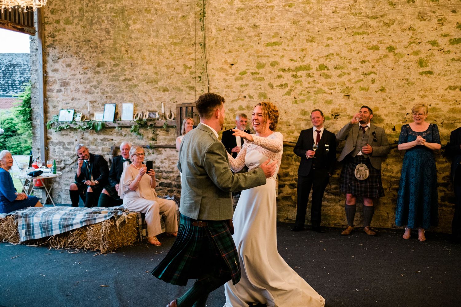 Wedding reception guests dancing and celebrating inside a stone-walled barn venue.