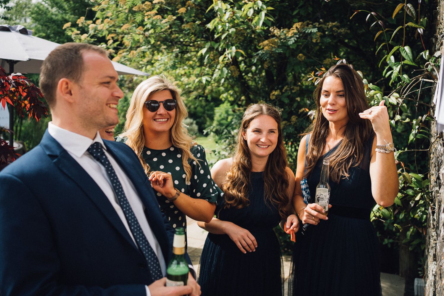 Wedding guests enjoying drinks and conversation at an outdoor garden party.