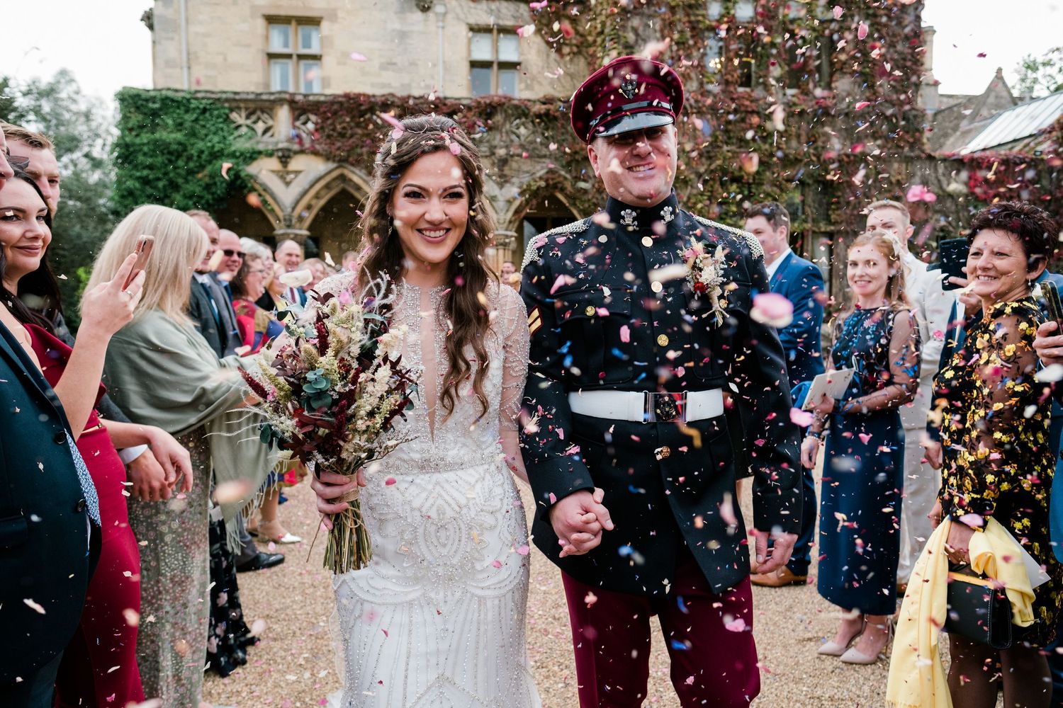 Wedding guests throwing confetti during an outdoor celebration at a stone building.