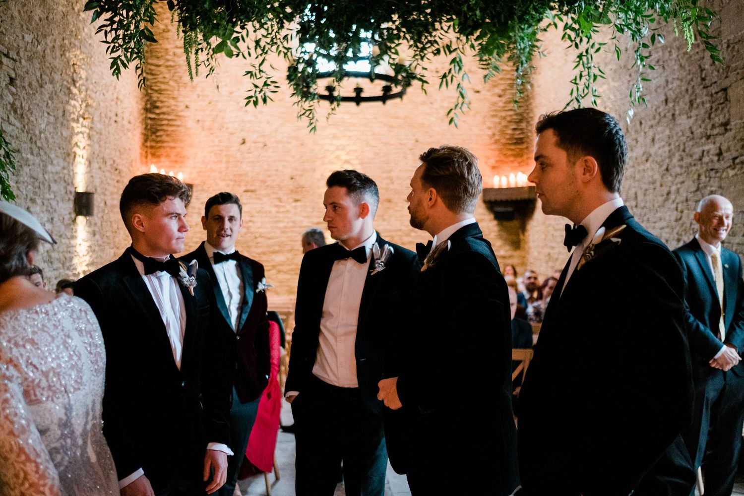 Formal event gathering in a rustic venue with stone walls and greenery.