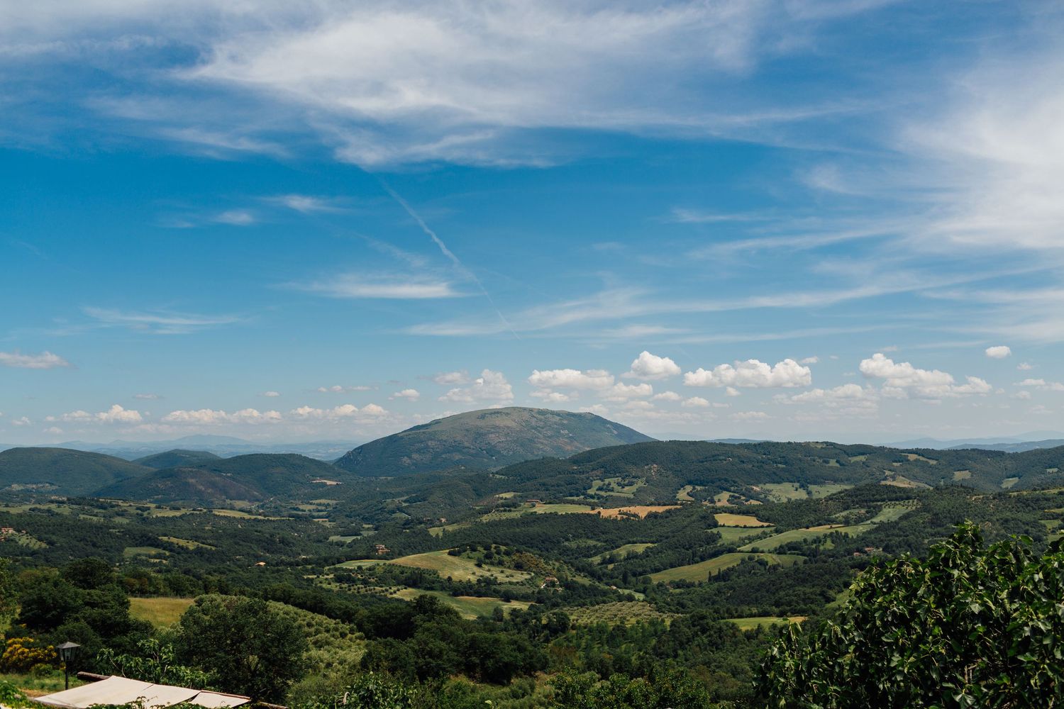 Scenic mountain landscape view with rolling hills and blue sky with wispy clouds.