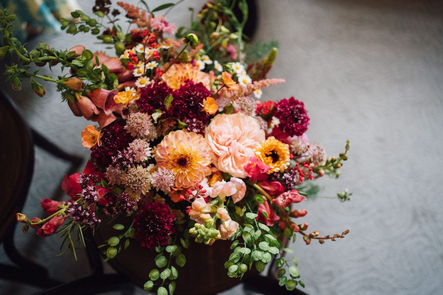 Vibrant floral arrangements featuring pink, orange, and burgundy blooms with cascading greenery on a light surface.