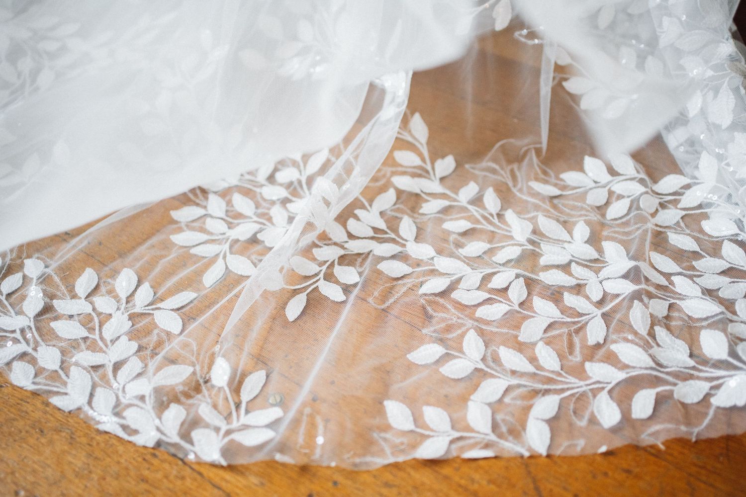 Delicate floral lace detail from the hem of a white wedding dress.