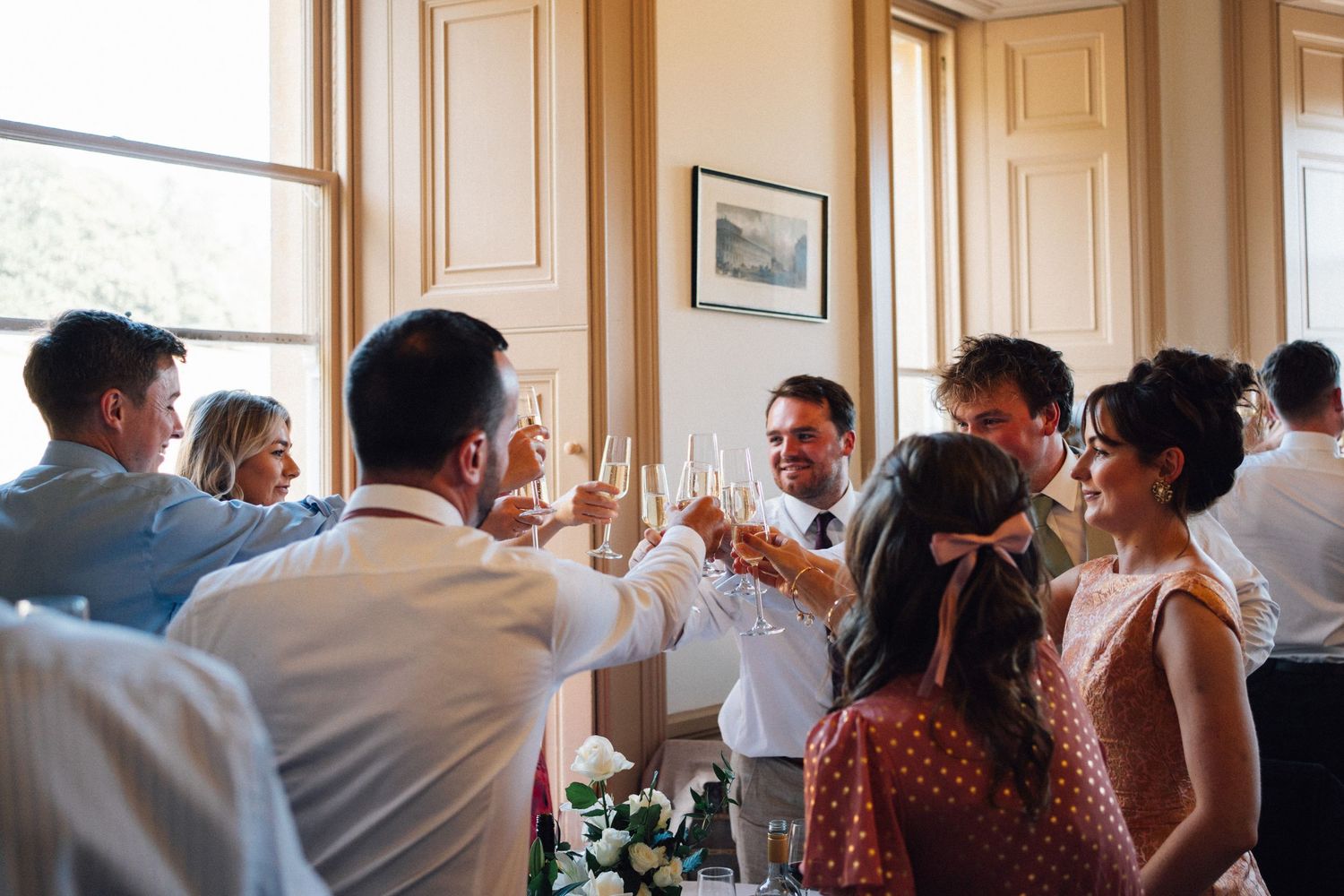Wedding guests raise their glasses in a celebratory toast during an indoor reception.