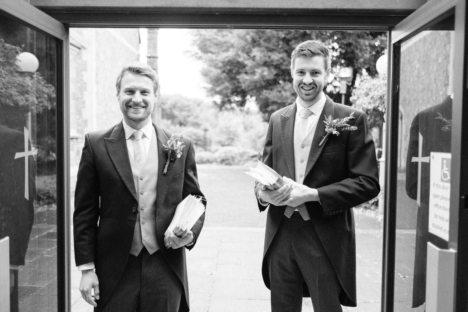 Wedding party members in formal attire pose together outdoors.