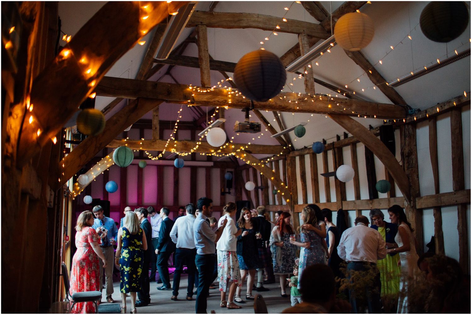 Rustic barn wedding venue decorated with string lights and balloons for an evening celebration.