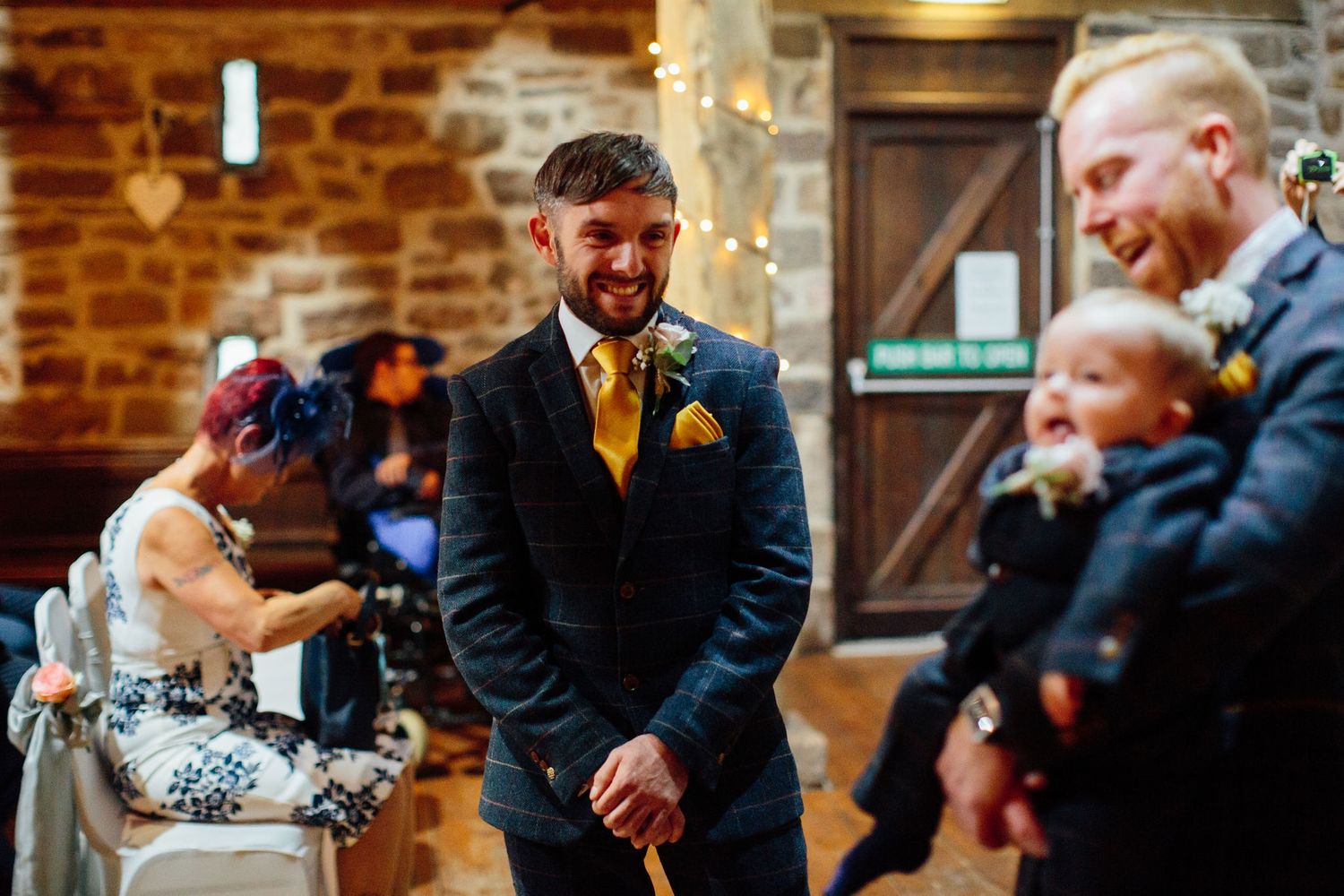 Wedding reception party with guests dancing and celebrating in a rustic brick-walled venue.