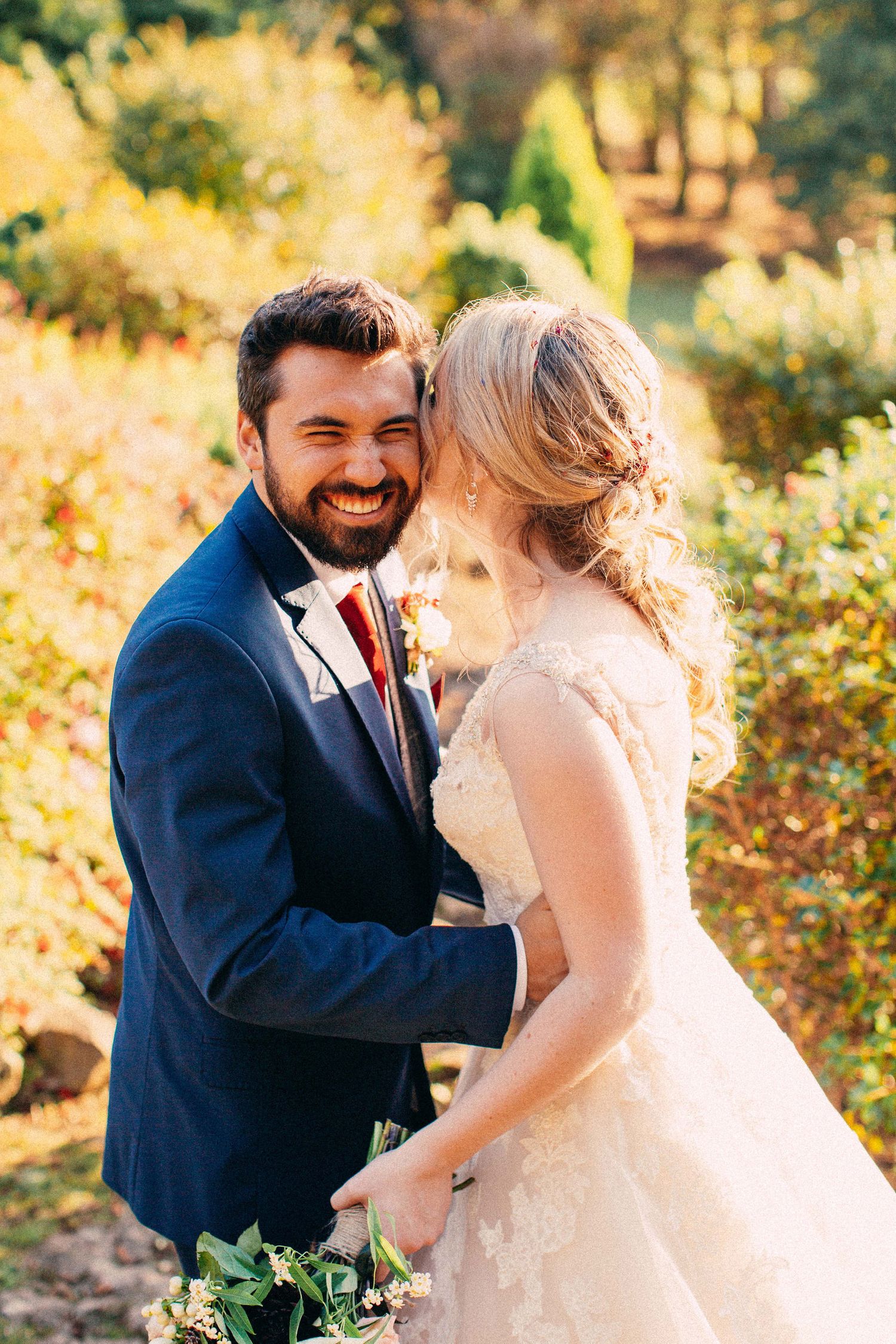 Romantic wedding portrait captured in warm sunlight with autumn colors in background.