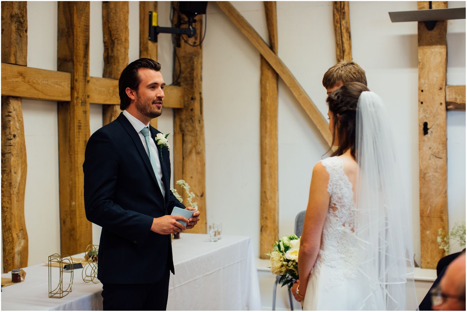 Wedding ceremony moments captured in a rustic wooden beam venue.