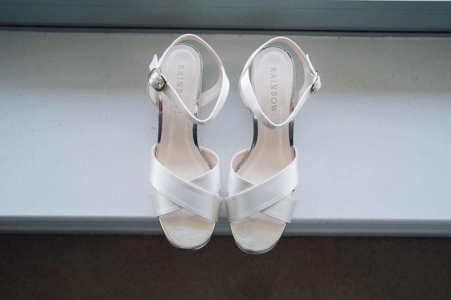 White bridal shoes displayed in a row against a gray background.
