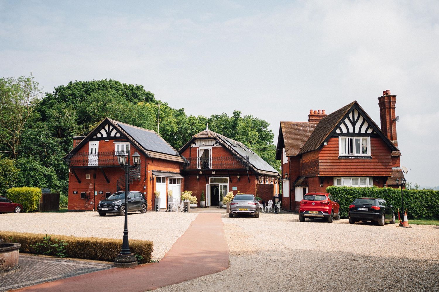 Panoramic view of traditional English Tudor-style buildings with brick chimneys and white trim along a countryside road.
