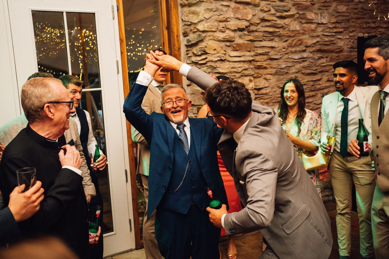 Celebratory moment at wedding reception with guests cheering and dancing.