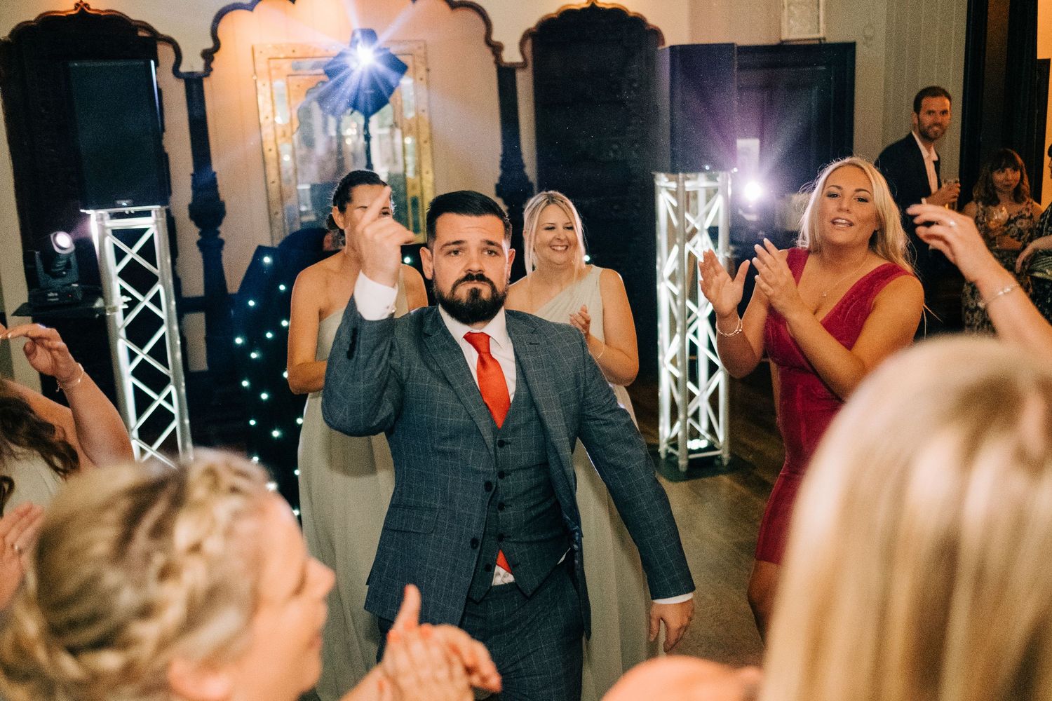 Indoor wedding celebration with dramatic lighting and guests enjoying the festivities.