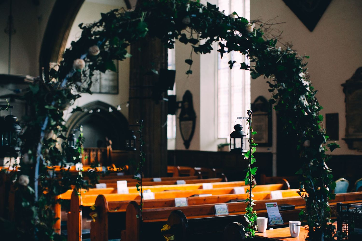 Dark atmospheric church interior with decorative greenery and warm lighting along the pews.