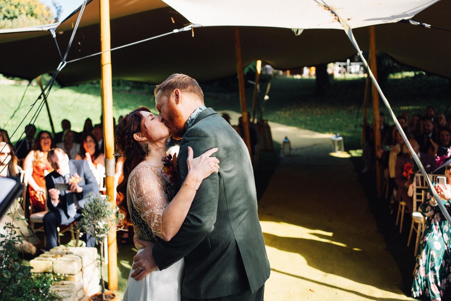 Wedding guests celebrate and dance together under an outdoor tent during a joyful reception celebration.
