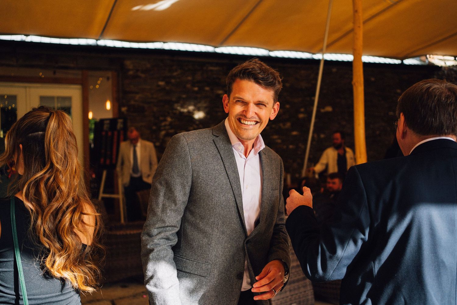 Business professionals networking and mingling at an evening cocktail reception in a dimly lit venue.