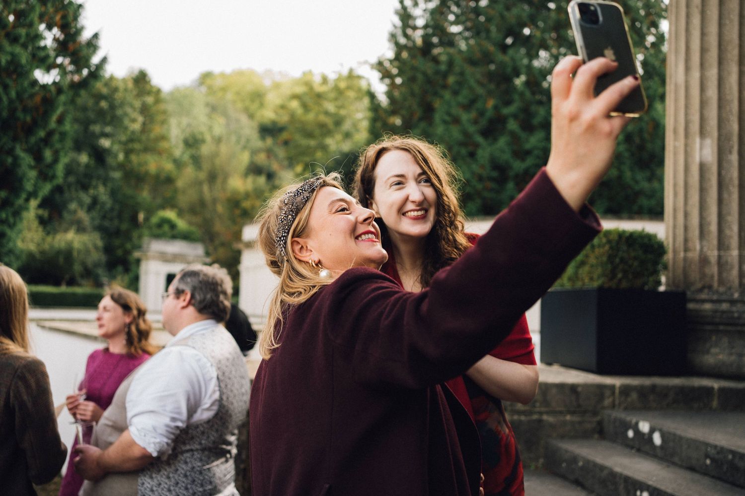 People gathered on stone steps outdoors taking selfies and photos during a celebration.