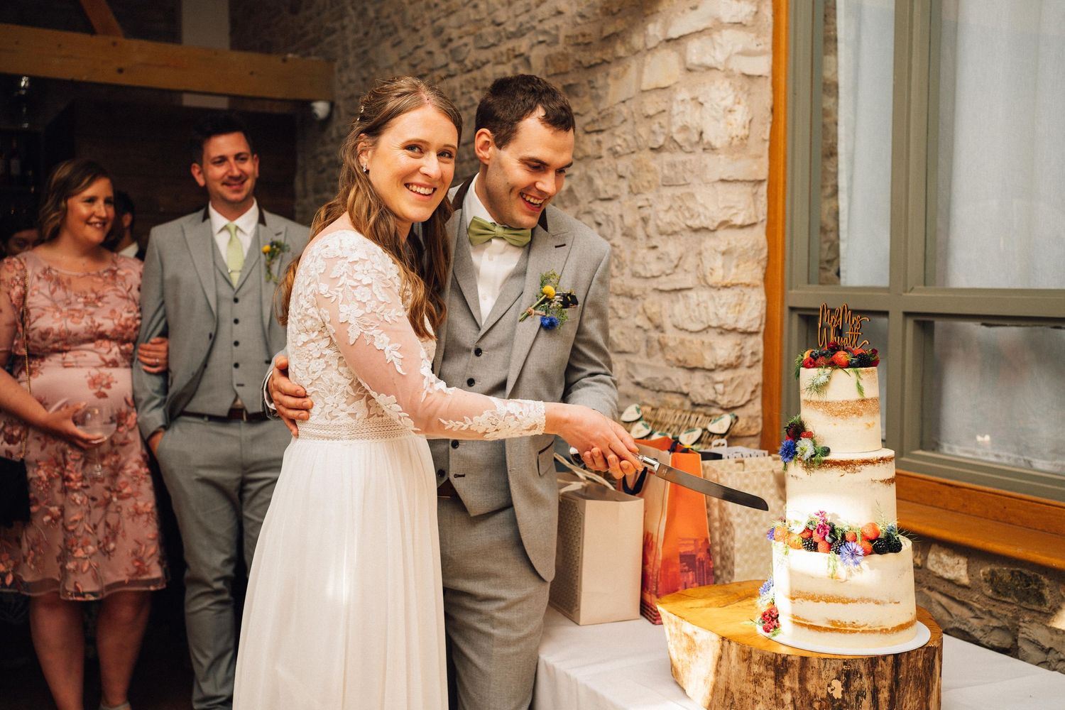 Wedding couple cutting their cake together at rustic stone venue.