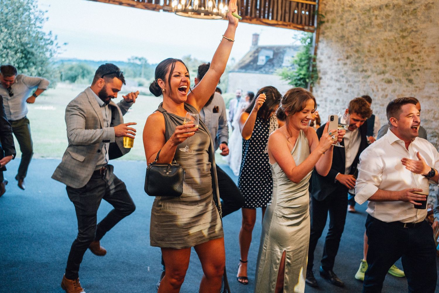 Wedding guests dancing and celebrating together on a dance floor at an indoor reception venue.